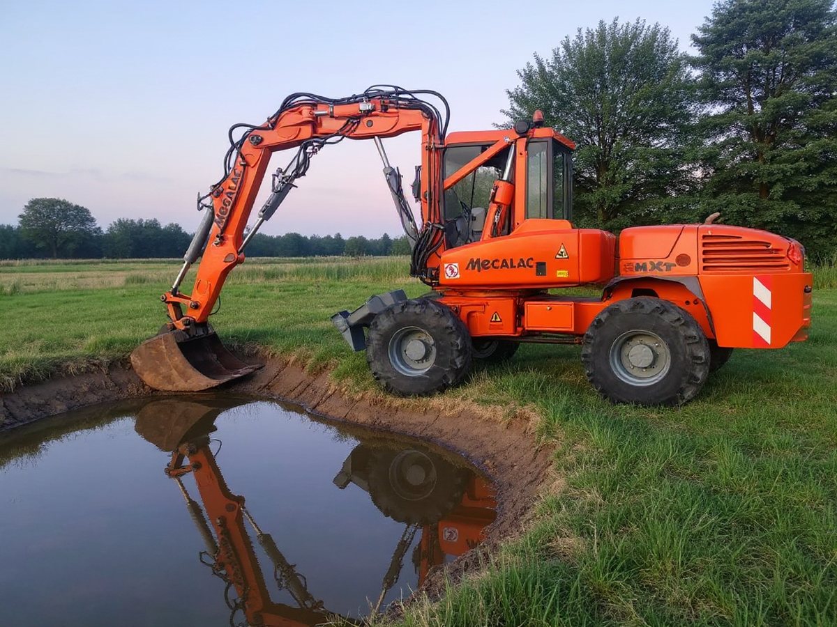 Koparka formuje skarpę nowo wykopanego stawu w ogrodzie